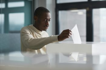 une homme senior vote en mettant le bulletin dans l'urne